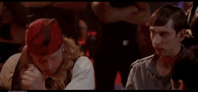 a man is holding another man 's arm in a crowd of people in a dark room .
