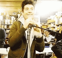 a man singing into a microphone in front of a sign that says joc