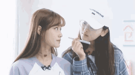 two young women are standing next to each other and one of them is holding a pen .