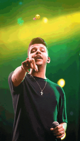 a man in a black shirt with a cross necklace is pointing