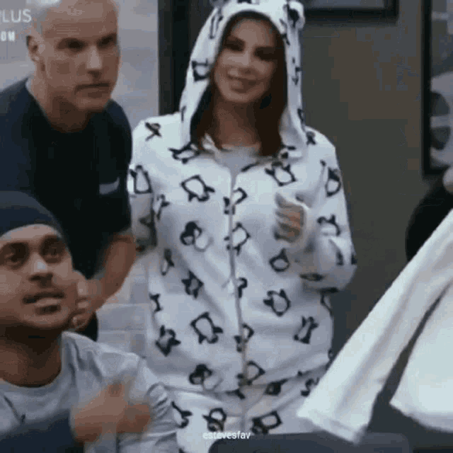 a woman wearing a hoodie with a leopard print is standing in front of a group of people .