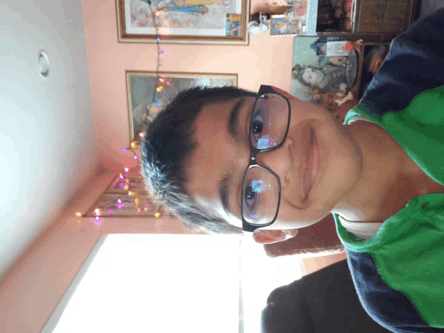 a young boy wearing glasses and a green shirt is smiling