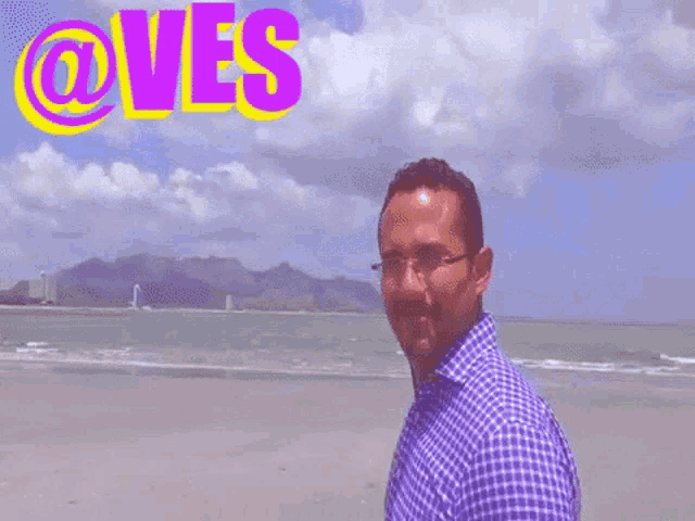 a man is standing on a beach with the word @ves behind him
