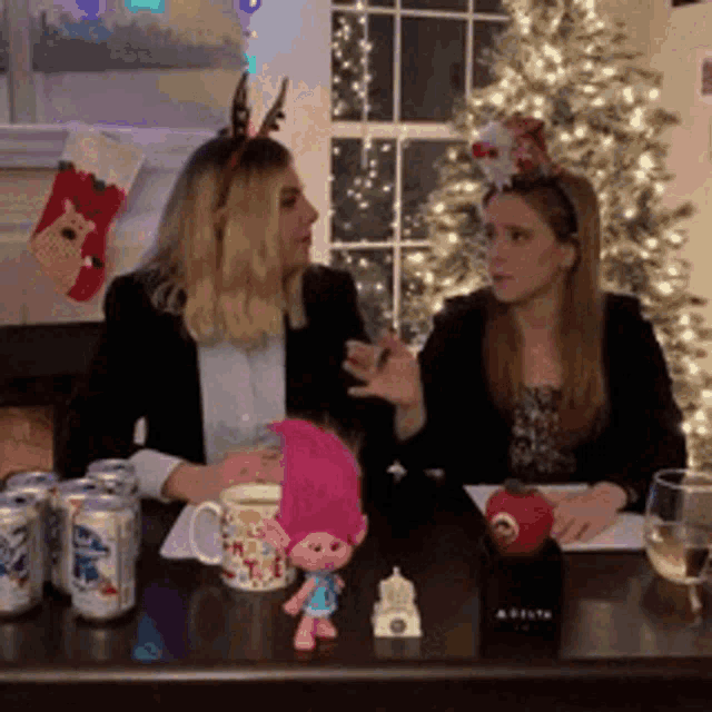 two women are sitting at a table with trolls and cans