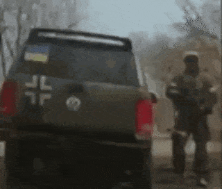 a soldier is standing next to a military vehicle on a street .