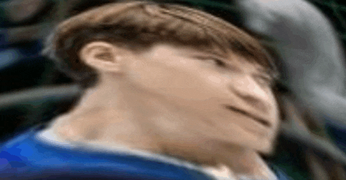 a close up of a person 's face with a blurry background and a blue shirt .