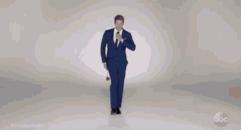 a man in a suit and tie is holding a rose and walking .
