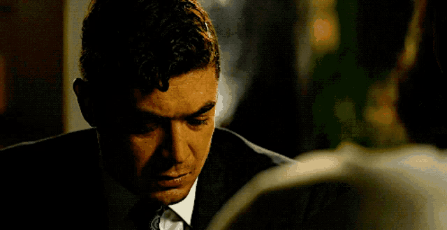 a man in a suit looks down at something