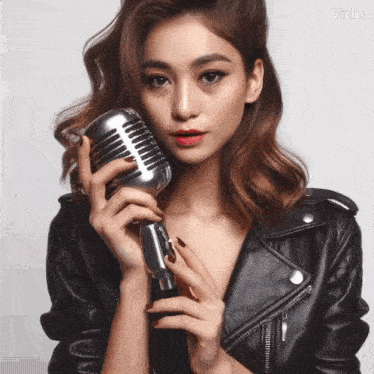 a woman in a leather jacket is holding a microphone in her hands