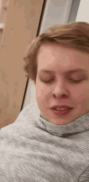 a close up of a person 's face with their eyes closed and a striped shirt on .