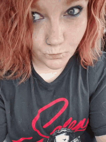 a woman with red hair is wearing a black t-shirt with a red letter o