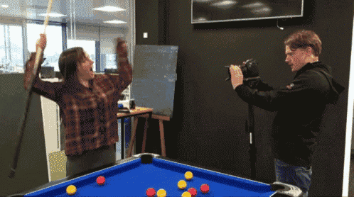 a man is taking a picture of a pool table with a woman holding a pool cue
