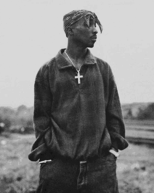 a black and white photo of a man with a cross necklace