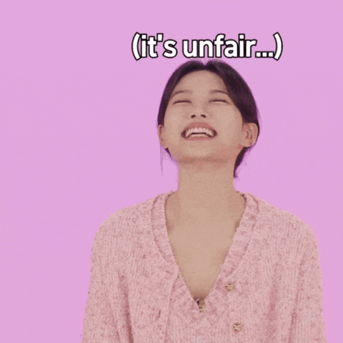 a woman in a pink sweater is smiling and says it 's unfair