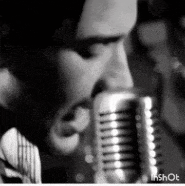 a black and white photo of a man singing into a microphone with the watermark inshot