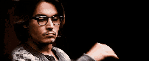 a man wearing glasses and a sweater has his hand on his chin and the words mas sera written below him .