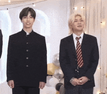 a man in a suit and tie is standing next to another man in a suit and tie .