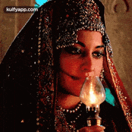 a woman in a veil is holding a lamp in her hand and smiling .