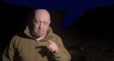 a man in a tan jacket is making a funny face in the dark
