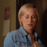 a woman is wearing a denim jacket and looking at the camera .
