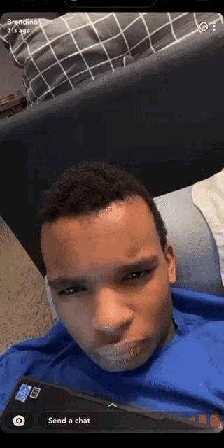 a boy is laying on a couch with a phone in front of him and a message that says send a chat on the bottom