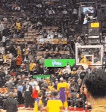 a basketball game is being played in front of a crowd of people in a stadium .