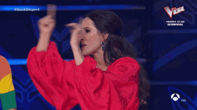 a woman in a red dress is dancing in front of a sign that says the voice