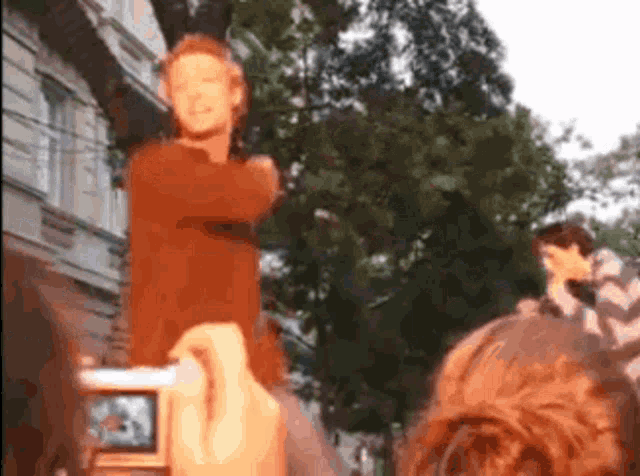 a man in an orange shirt is being photographed by a camera