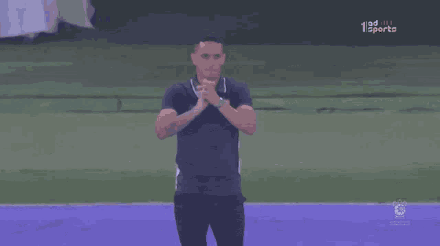 a man stands on a purple field in front of a screen that says 123sports