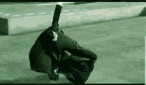 a man is sitting on the ground with a suitcase on his head .
