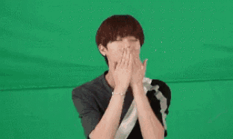 a young man with red hair is making a heart shape with his hands .