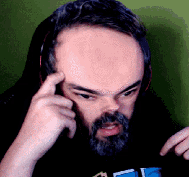 a man with a beard is wearing headphones and has his hand on his head