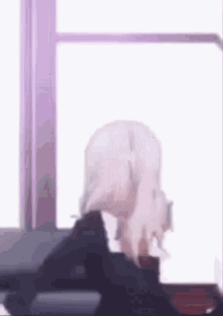 a girl with white hair is sitting in front of a window and looking out .
