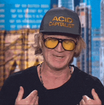 a man wearing sunglasses and a hat that says " acid capitalist "