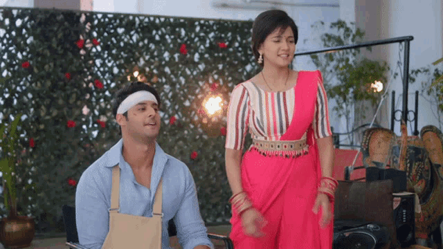 a man with a bandage on his head is sitting next to a woman in a pink saree