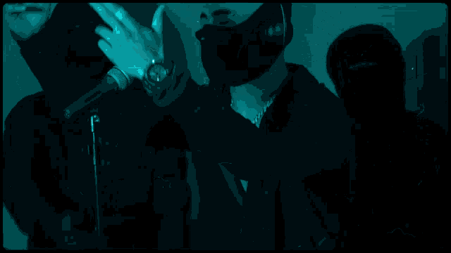 a man wearing headphones and a mask stands in a room with other people