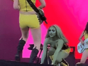 a woman in a yellow outfit is kneeling down on stage