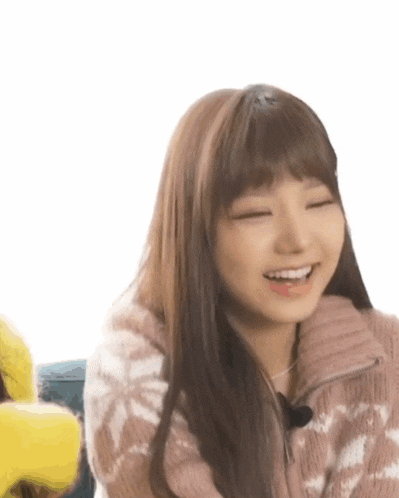 a close up of a woman wearing a pink sweater and smiling