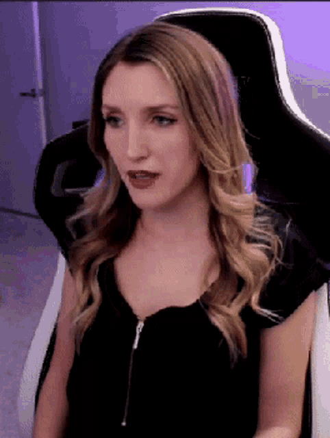 a woman in a black shirt is sitting in a chair with her mouth open