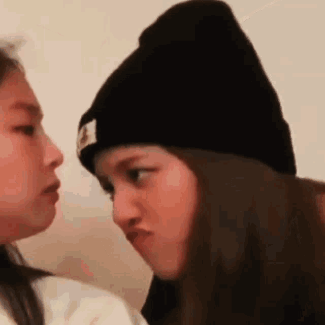 two girls wearing hats are looking at each other .