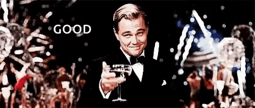 a man in a tuxedo is holding a glass of champagne in front of a crowd of people .