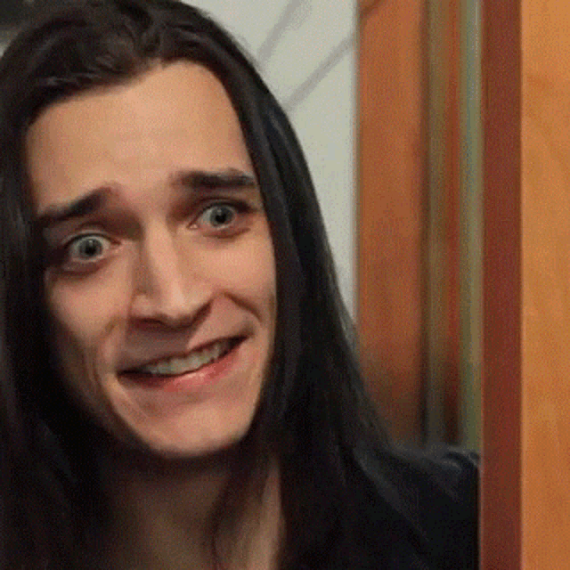 a close up of a man with long hair smiling .