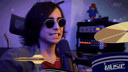 a man wearing sunglasses is playing a drum set with the word music on it