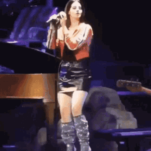 a woman in a leather skirt is singing into a microphone