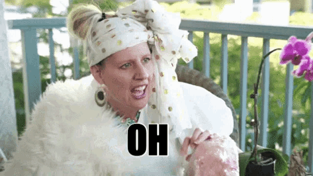 a woman wearing a white fur coat and a head scarf is sitting on a porch and making a funny face .