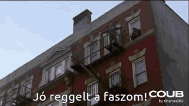 a man is hanging from a fire escape on a building
