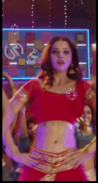 a woman in a red top and gold skirt is dancing