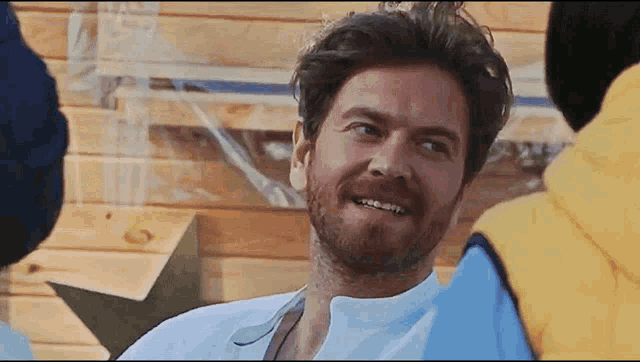 a man with a beard wearing a white shirt smiles