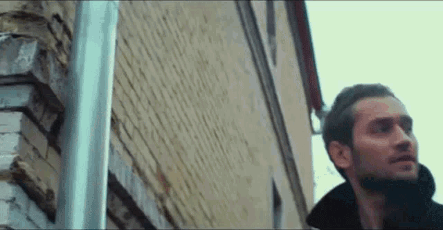a man is standing next to a pole in front of a brick building .