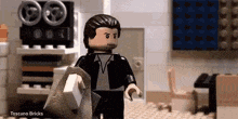 a lego man in a suit and tie is walking in a room .